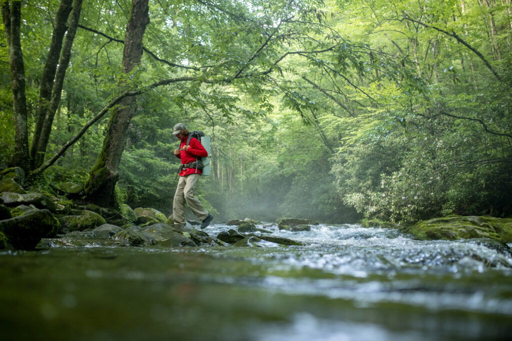 man hiking through a river in the Smokies