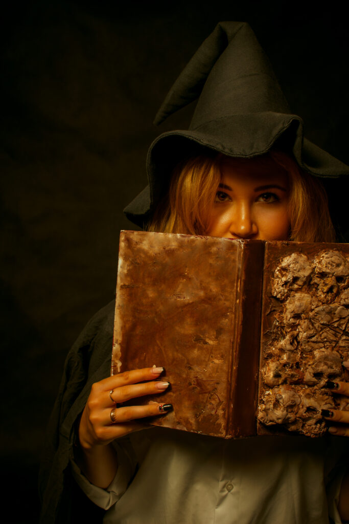 Cute witch posing over dark background with spell book
