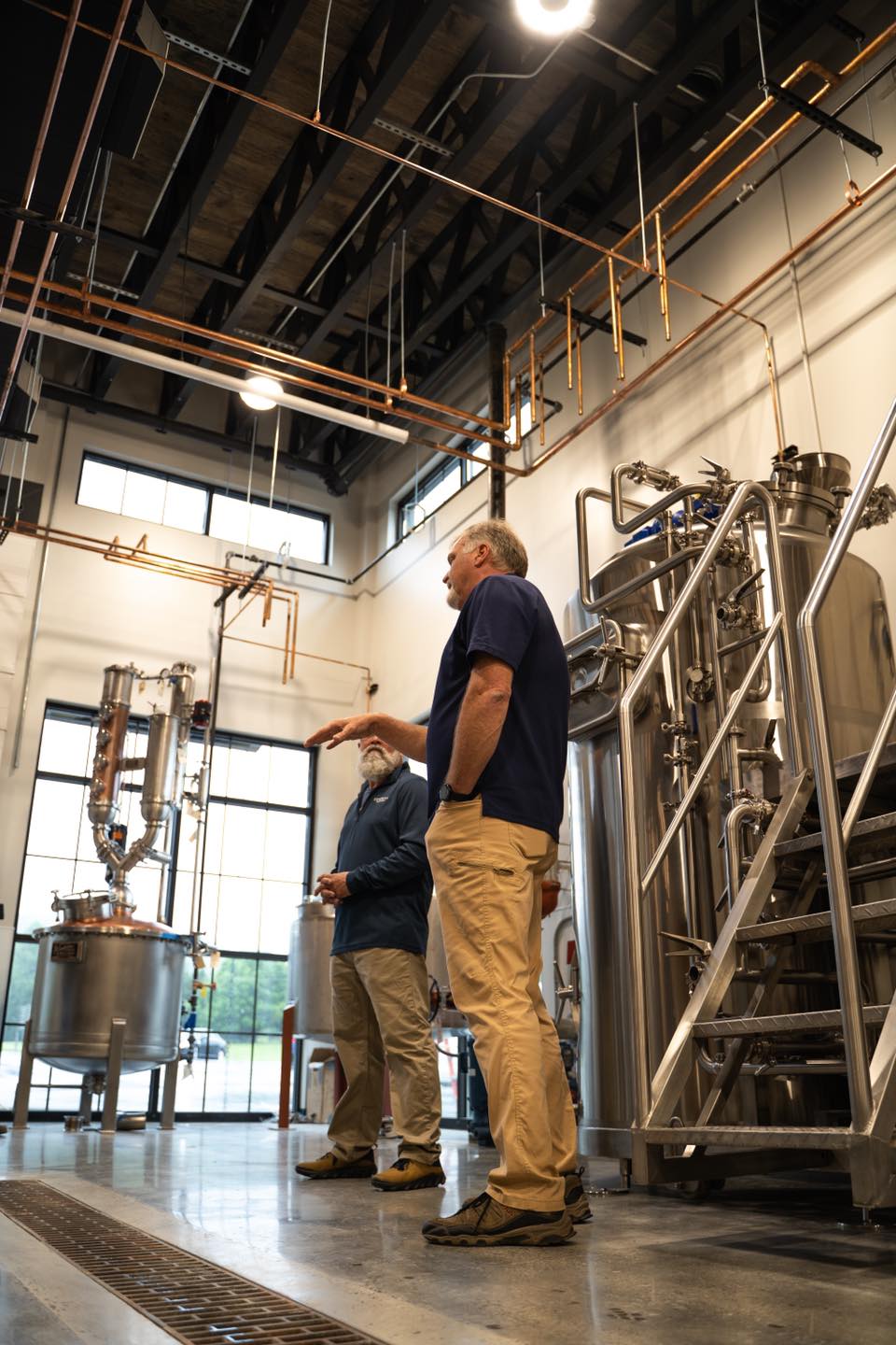 Master Distiller of Company Distilling stands in front of steel still.