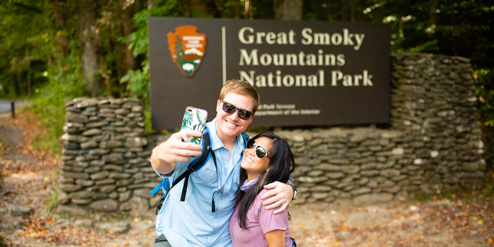 A couple taking a selfie in front of Great Smokey Mountains National Park sign